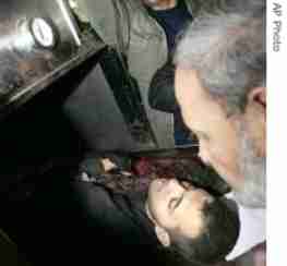 Senior Hamas leader Mahmoud Zahar, right, looks at the body of his son Hussam, 24, at the morgue <font face=Arial size=-2>(Source: voanews.com)</font>