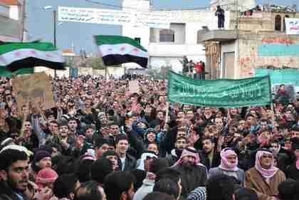 Anti-Syrian regime protesters in Homs on Friday.  The Arabic banner reads, 'No God only God, Mohammed Prophet of God.'  The same day, regime forces with mortars barraged residential buildings, killing 30 people in their homes. (AP)