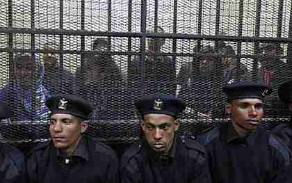 Policemen sit in front of a cage holding Egyptian employees of pro-democracy groups on trial (AP)