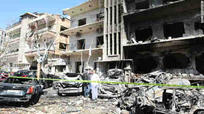 Syrian security officers inspect the scene of a destroyed building following twin bomb attacks in Damascus on Saturday. (CNN)