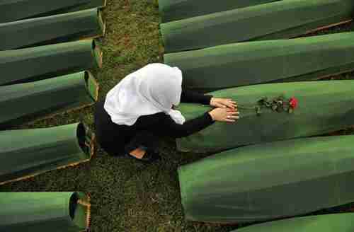 A Bosnian Muslim survivor of the 1995 Srebrenica massacre, mourns a relative in a casket buried on Thursday (AFP)