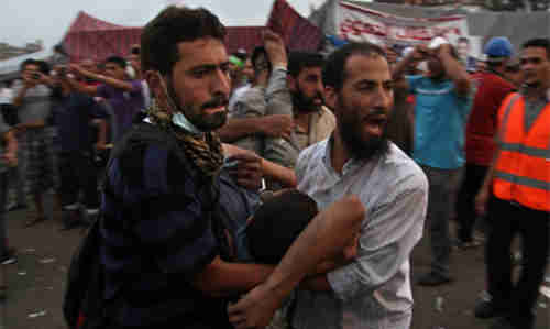 Pro-Morsi supporters carry an injured man to a field hospital on Saturday (AP)