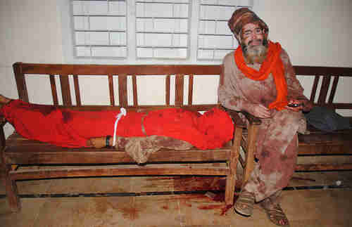 A Pakistani covered with blood sits with the body of a blast victim on Thursday (AFP)