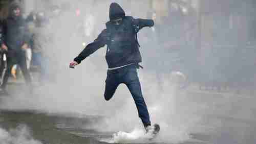 A youth kicks a teargas canister in Paris on Thursday during a protest against both Le Pen and Macron (AFP)