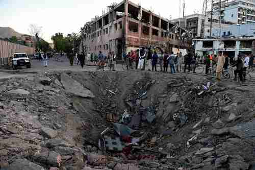 Afghan security forces and residents stand near the 13ft deep crater left by Wednesday's truck bomb attack in Kabul (AFP)