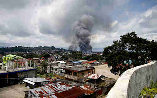 Fire rages at several houses following airstrikes by Philippine Air Force bombers on May 27 (AP)