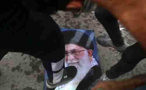 Protesters trample a portrait of Iran’s Supreme Leader Ayatollah Ali Khamenei, during the storming and burning of the Iranian consulate in Basra on Friday (AP)