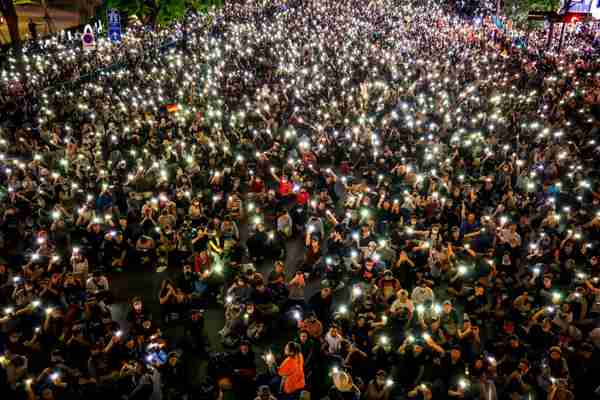Pro-democracy protesters in Bangkok hold up their mobile phones as they rally in defiance of the government's emergency declaration (EPA)