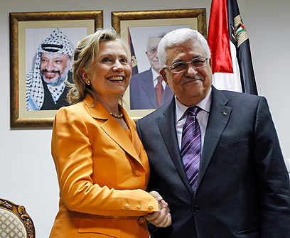 Mahmoud Abbas shakes hands with Hillary Clinton.  In the back is a picture of Yasser Arafat (Ynet)