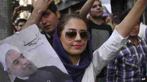 Female supporter holding up picture of Rouhani on Saturday.  Her loose hairscarf is an act of rebellion against the hardliners.  (BBC)