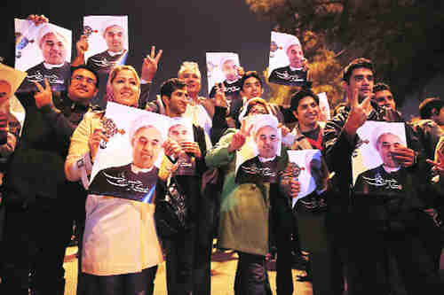 Jubilant Iranians holding posters of president Hassan Rouhani welcome the return of victorious negotiator Javad Zarif in Tehran on Sunday (AP)