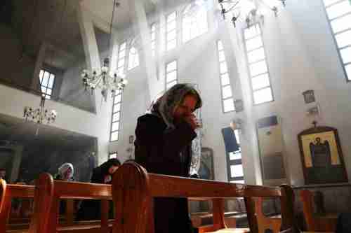 An Assyrian woman in church prays for Christians abducted by ISIS (Reuters)
