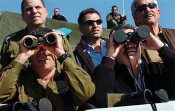 Israel's Defense Minister Amir Peretz (right) in 2007 looking through binoculars with the lens cap on. On the left is the army's new Chief of Staff, Lt. Gen. Gabi Ashkenazi. They're reviewing a military drill in the Golan Heights.