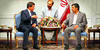 Turkish Foreign Minister Ahmet Davutoglu (L) talks to Iranian President Mahmoud Ahmadinejad