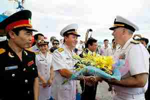 Col. Nguyen Van Lam, center, greets U.S. Rear Admiral Tom Carney with flowers on Friday (Reuters)