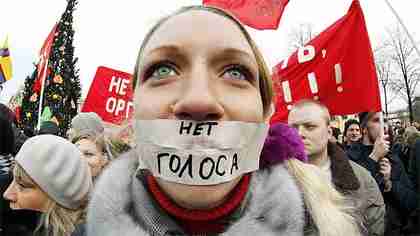 A protester with her mouth taped shut against Putin.  The words read 'No vote' (AP)