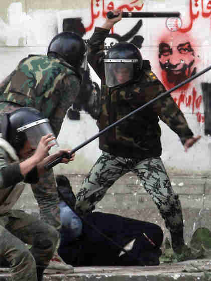 In Tahrir Square, soldiers beating a veiled woman protester