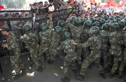 Chinese paramilitary police try to prevent demonstrators from breaking through a fence set up outside the Japanese Embassy in Beijing (AP)