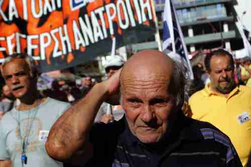 An elderly man marches with protesters in front of the Greek parliament on Tuesday (AFP)