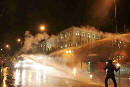 A protester on Wednesday about to throw a petrol bomb is struck by water cannon (Guardian)