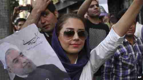 Female supporter holding up picture of Rouhani at a June campaign event.  Her loose hairscarf is an act of rebellion against the hardliners.  (BBC)