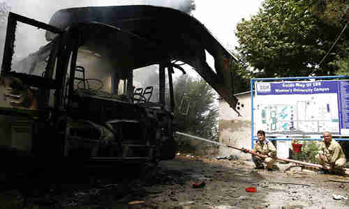 Bombed out bus next to women's university campus sign on Saturday (Dawn)