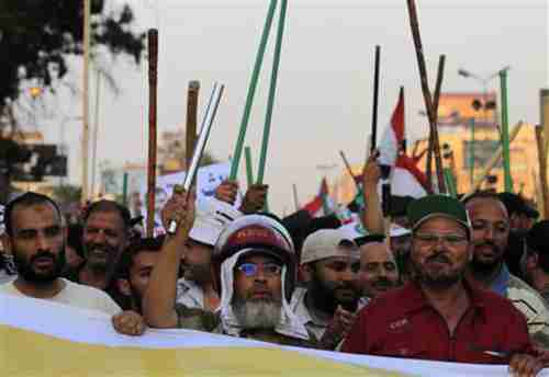 Muslim Brotherhood members wave sticks and shout slogans in support of president Mohamed Morsi (Reuters)