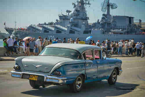 A 1950s U.S. car passes Cubans waving at the Russian 'Moskva' missile cruiser in Havana on Saturday (AFP)