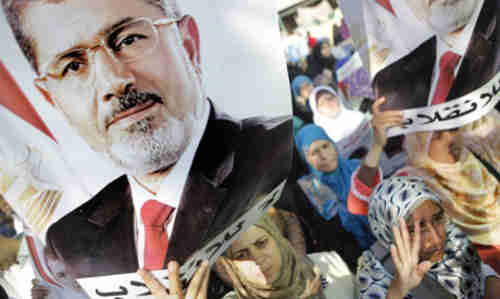 Morsi supporters hold posters with Morsi's face and words in Arabic that read 'No to the coup' on Monday (AP)