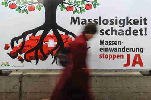The caption says: 'The excess is harmful! Stop mass immigration - YES.'  I'm not sure what the tree symbolizes, but in the picture its roots are strangling Switzerland.