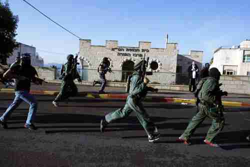 Israeli security forces run in front of the synagogue that was attacked on Tuesday