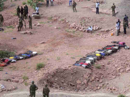 Soldiers of Kenyan Defense Forces look over the bodies of some 36 Kenyans killed by al-Shabaab on Tuesday (AP)