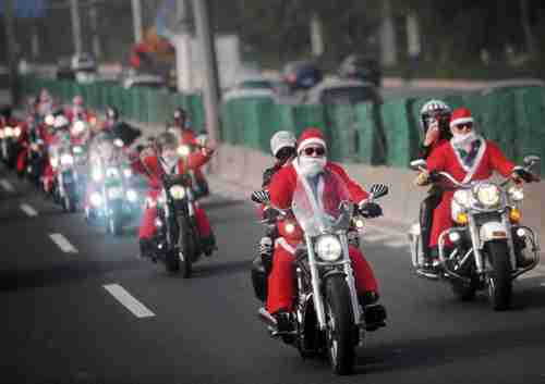Owners of Harley-Davidson motorcycles wearing Santa Claus costumes ride along a street to give presents to elders at a nursing home during a promotional event celebrating Christmas in Guangzhou, Guangdong province on Dec. 24, 2014 (Reuters)