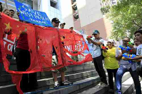 Anti-Chinese environment activists in Manila protest in front of the Chinese embassy, shooting Chinese flags with water guns (Reuters)
