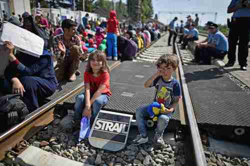 Two children sit on the tracks as hundreds of migrants wait for the train in Tovarnik, Croatia, just across the border from Serbia (Getty)