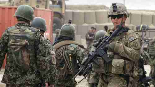 Afghan soldiers, left, walk past a U.S. Army soldier in a military base in 2012 (AP)