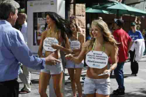 An October 2013 promotional campaign for Colorado HealthOP features hot, scantily clad girls carrying signs saying, 'Without health insurance, you're exposed.' (AP)