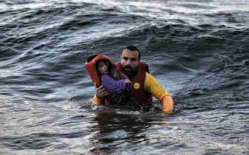Refugee father in Aegean Sea scrambles for shore with his son.  More than 100 children have drowned in the Aegean over the last two months.  (Kathimerini)
