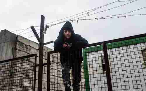 A boy on a fence watches thousands of Syrians massed on the border with Turkey in the cold and rain (AFP)