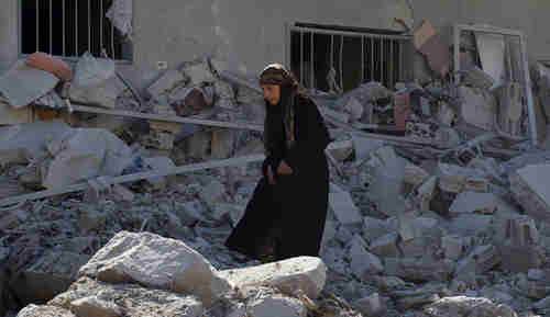 A woman makes her way through the rubble of damaged buildings after Syrian government airstrikes on Friday (Reuters)