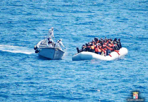 Italian Navy personnel, left, approach a rubber dinghy filled with migrants in the Sicily channel, Mediterranean Sea (AP)
