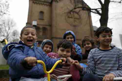 Migrant children from Syria pose in front of a Protestant church in Oberhausen, Germany, November 19, 2015 (Reuters)