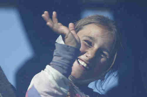 An Iraqi Yazidi girl waves from a bus as she and her family leave the Idomeni refugee camp and head for another camp in Greece on Tuesday (AP)
