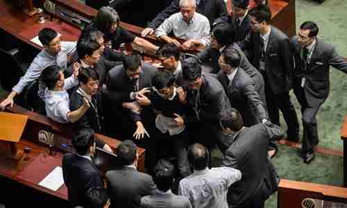 Newly elected lawmaker Baggio Leung is restrained by security while attempting to deliver his oath of office (AFP)