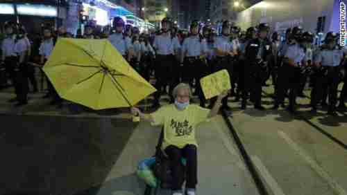 A protester raises a yellow umbrella in front of a line of police officers in Hong Kong on Sunday